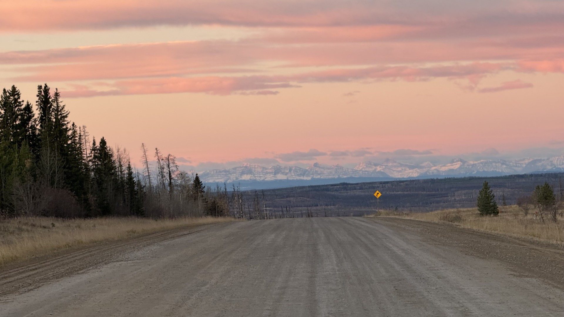 Gravel road leading toward distant mountains in pastel light.